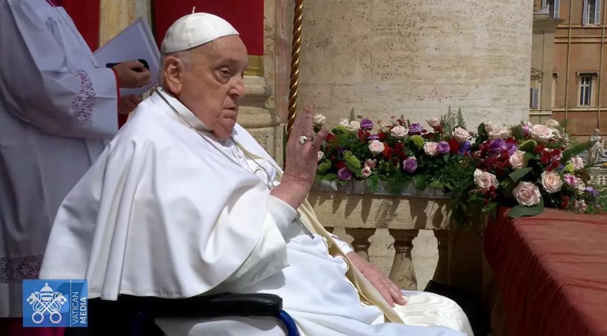Papa Francisc în scaun cu rotile cu mâna dreaptă ridicată și flori colorate în fundal