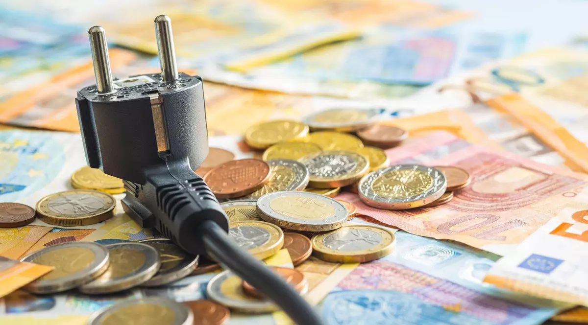 Ideea de scumpiri, bani imp[;tia'i pe o masă alături de un intrerupător electric