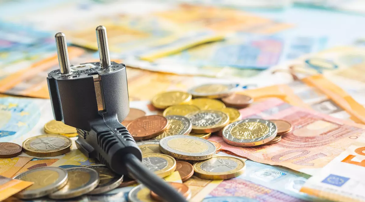 Ideea de scumpiri, bani imp[;tia'i pe o masă alături de un intrerupător electric