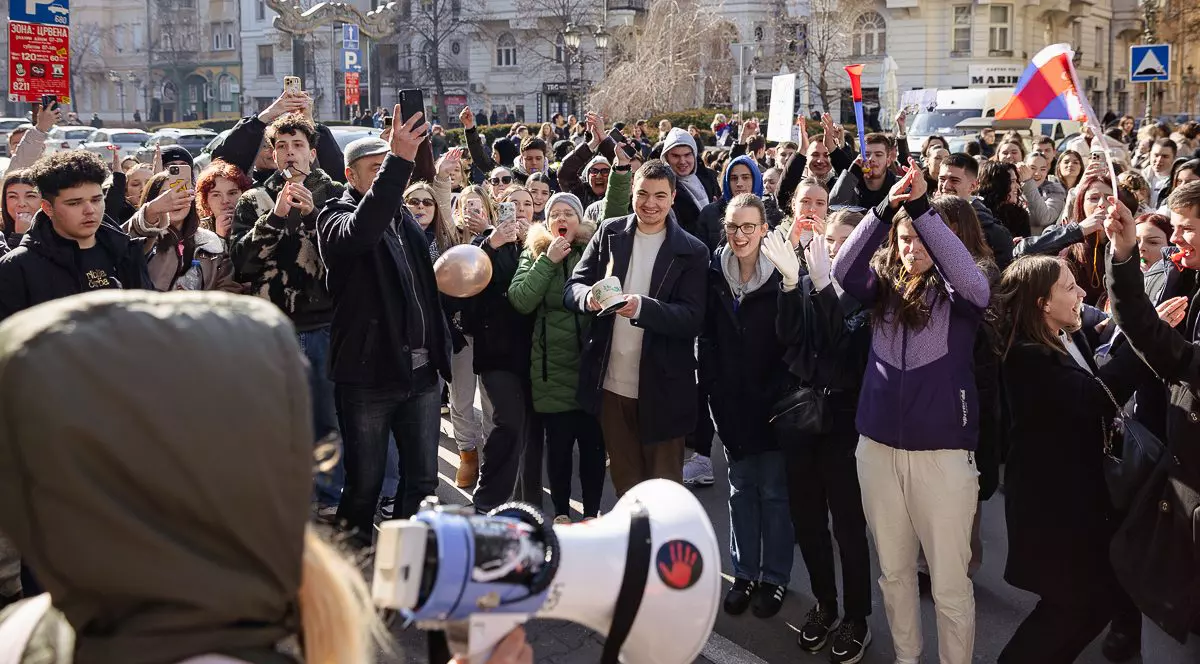 Protest studenți Novi Sad. In imagine se vede o multime de studenti care protesteaza, ia rin fata lor o persoana cu portavoce care pare sa dea tonul scandarilor