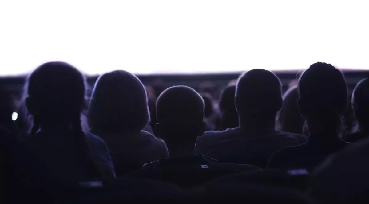 Captură din mijloc cu siluete de oameni din spate care se uită la cinema sau spectacole cu un spațiu gol alb