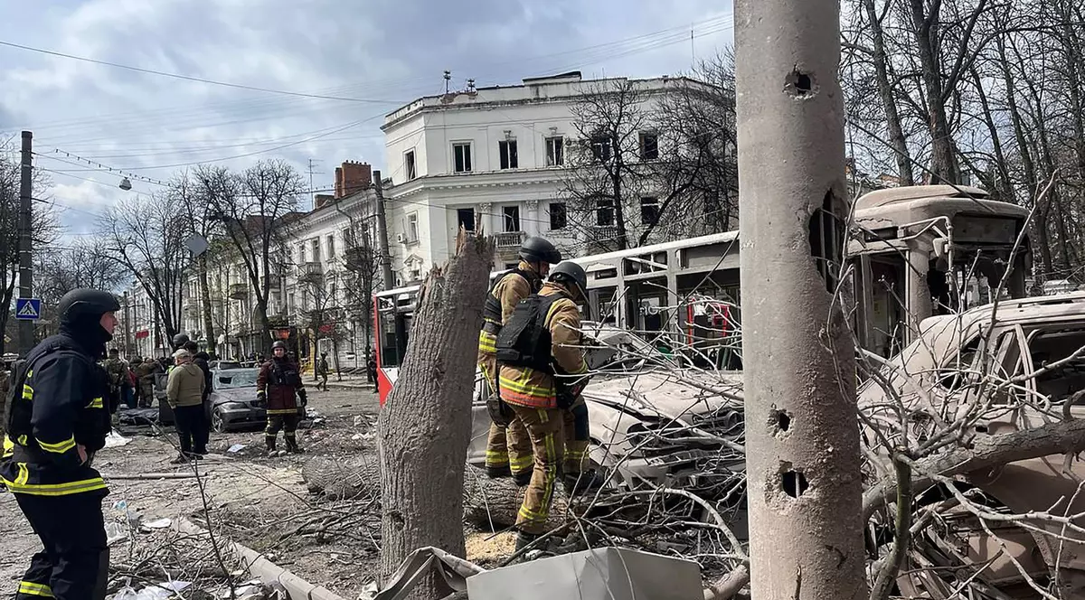 Trei salvatori ucraineni surprinși pe o stradă din Sumî, după atacul Rusiei. În imagini pot fi văzuți copaci la pământ și mașini distruse