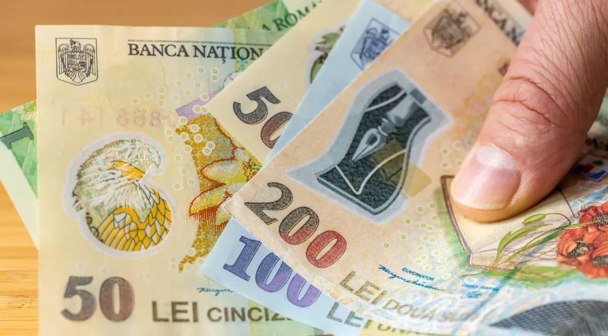 Imagine creativă cu un bărbat care ține în mână mai multe bancnote românești