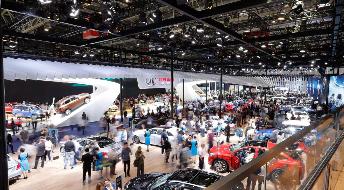 showroom masini chinezesti unde sunt foarte multe persoane care studiaza mai multe masini expuse