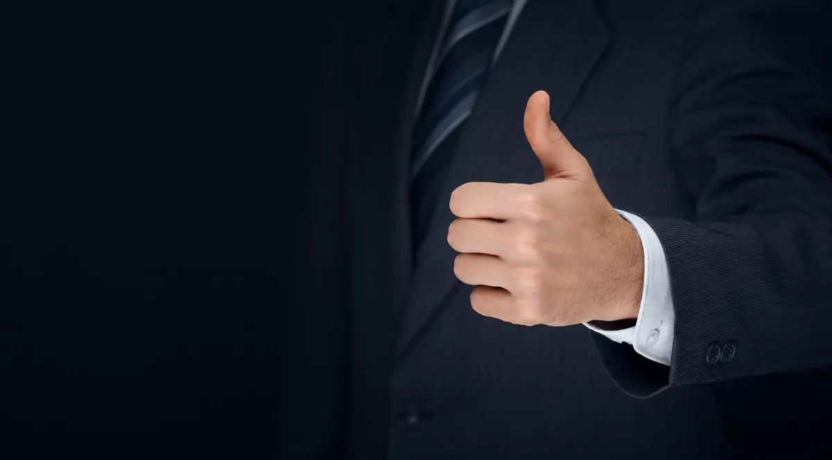 Barbat imbracat la costum bleumarin care arata semnul ok cu mana stanga