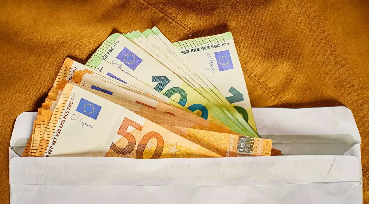 Bancnote euro în plic alb, vedere de sus. Close up de bani cash pe fundal maro. Concept de corupție, mită și plăți ascunse în numerar