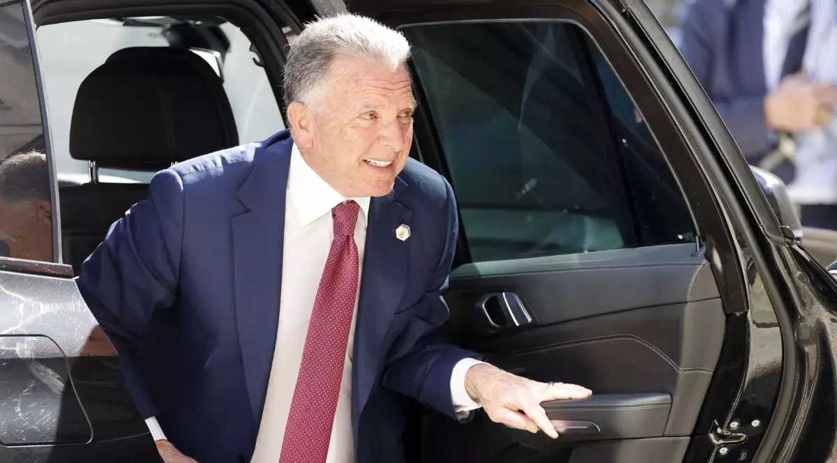 Steve Witkoff coborând dintr-o mașină, cu mâna pe portieră, îmbrăcat într-un costum bleumarin, o cămașă albă și o cravată roșie