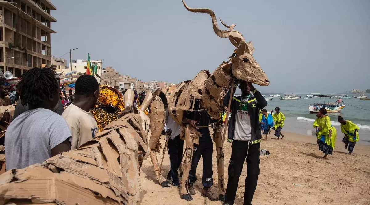 Un păpușar stă lângă păpuși de animale în mărime naturală, parte a proiectului de artă publică și acțiune climatică Herds, pe plaja Ngor din Dakar, la 26 aprilie 2025.