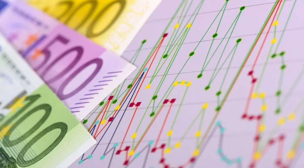 Graficul unei burse, cu linii verzi, galbene și roșii, alături de bancnote în euro