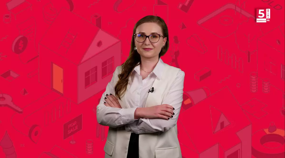 Corina Vârlan, prezentatoarea 5 știri imobiliare.ro, într-un sacou bej, cu mâinile împreunate.