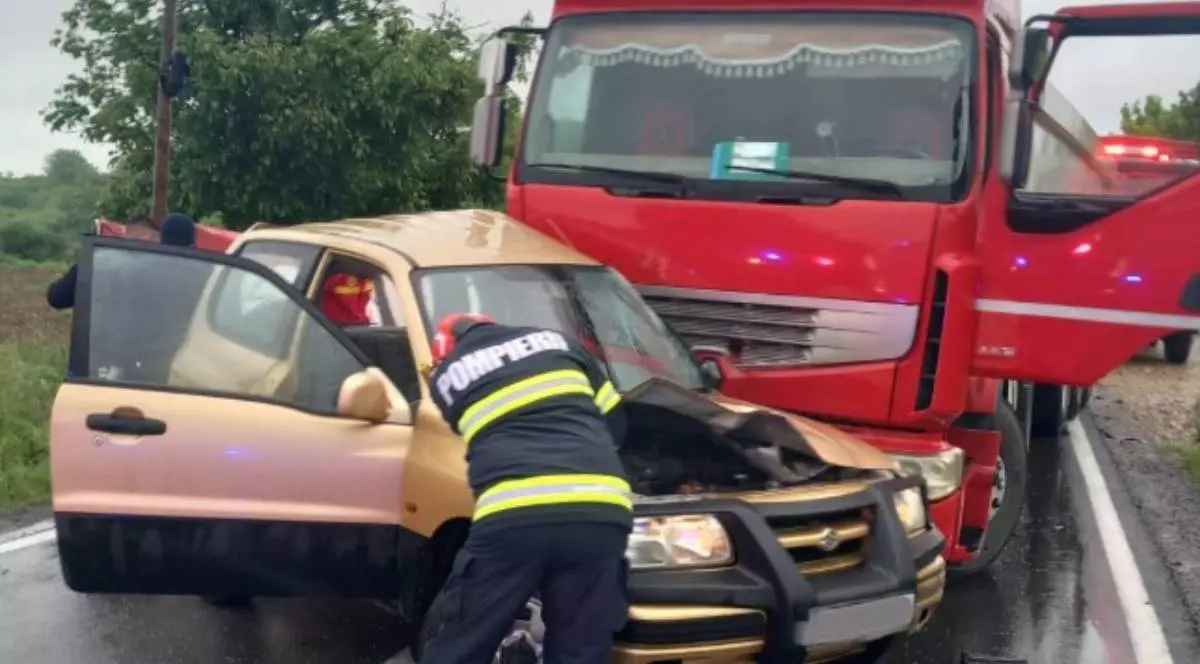 Un echipaj de pompieri care intervine la mașina accidentată strivită de camionului de la Sarcău.