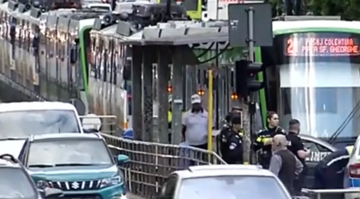 În centrul imaginii se observă un peron de tramvai unde sunt mai multe persoane, printre care și câțiva polițiști, în urma unui accident rutier.