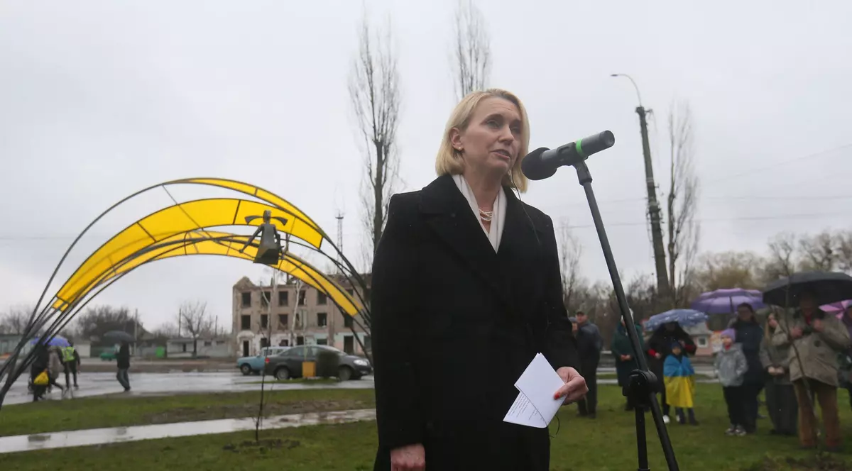 o femeie blondă vorbește la un microfon într-un parc