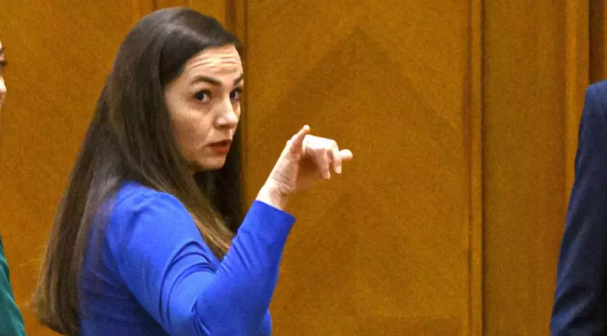 În imagine este ilustrată o femeie cu părul șaten, îmbrăcată în albastru.