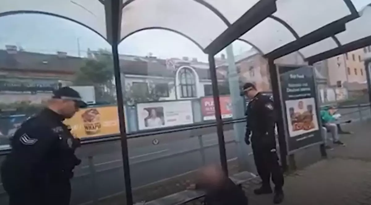 În imagine este ilustrat un bărbat care se află sub o bancă. Lângă acesta se află doi polițiști