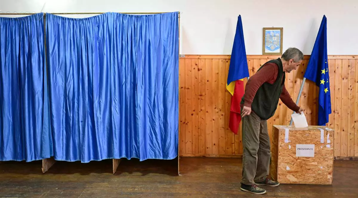 Un bărbat în vârstă, în timp ce se află în secția de vot și introduce buletinul ștampilat în urnă, la alegeri în România