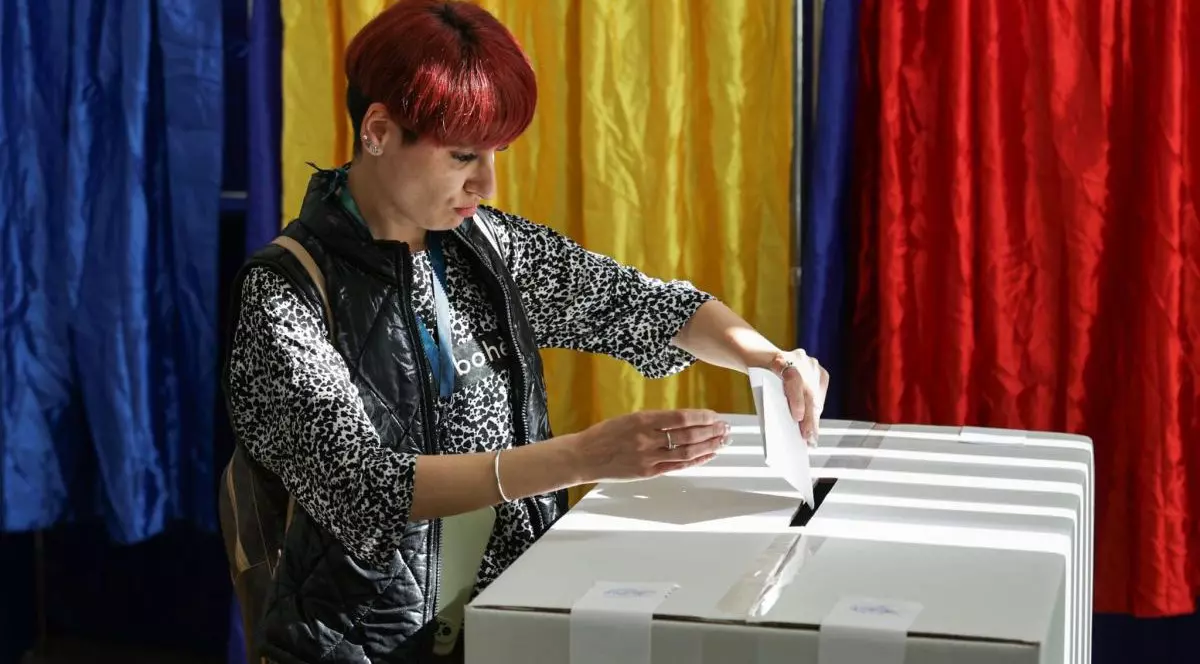 O tânără cu bluză și vestă bagă votul în urnă la alegerile prezidențiale din 4 mai 2025, București