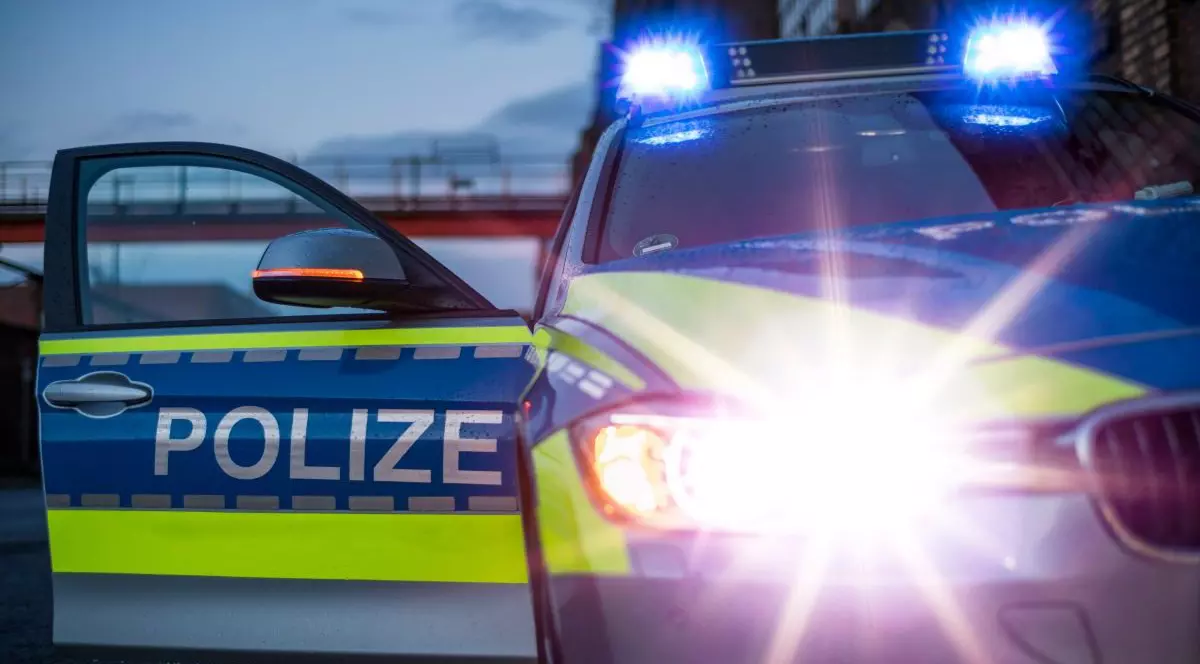 O mașină de poliție cu girofarurile aprinse și o ușă deschisă, în apopiere de fluviul Rin, în Germania