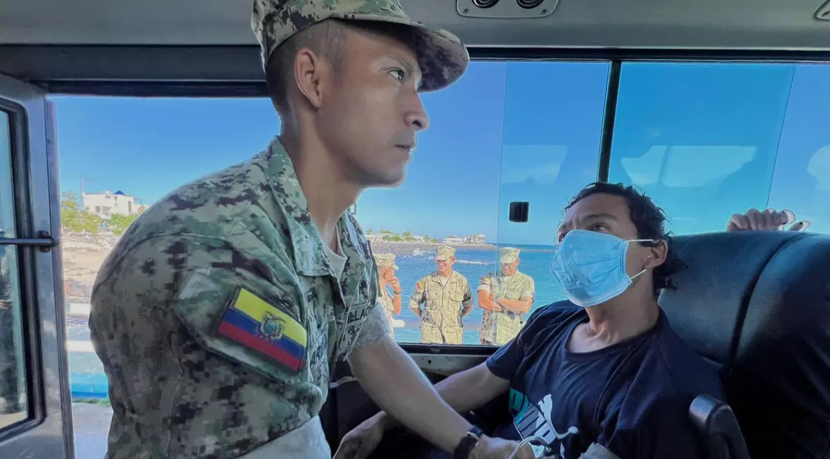 În imagine este ilustrat un bărbat în uniformă militară care îi ia tensiunea unui bărbat care poartă mască.