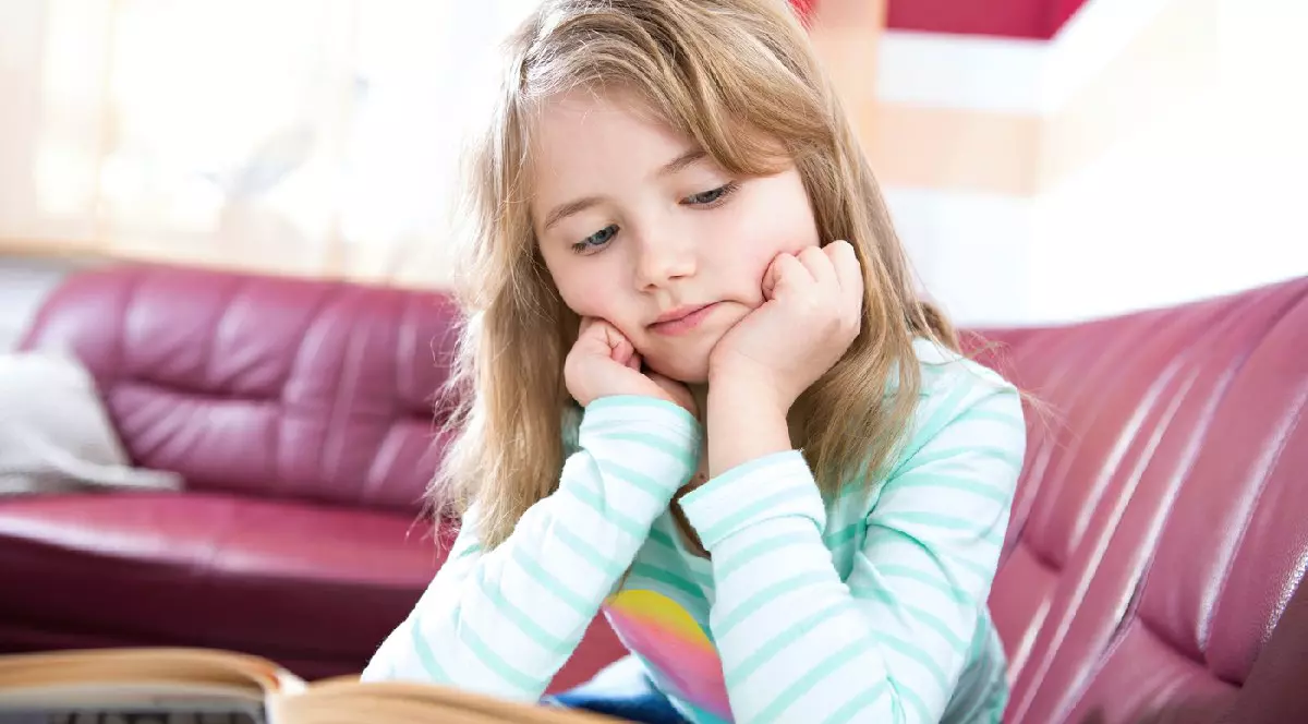 Fetiță care citește o carte acasă