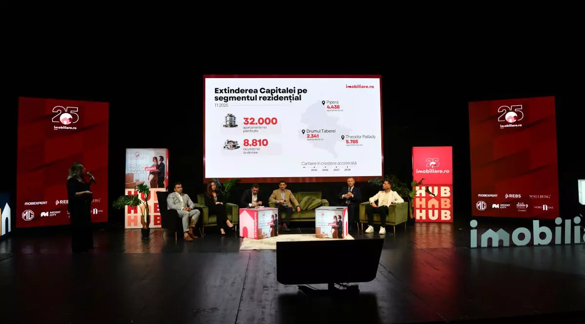 Dezvoltatori imobiliari, pe scena Imobiliare.ro HUB Național 2025, așezați pe scaune, cu un panou pe spate unde este afișat numărul 32.000 care indică câte apartamente vor fi construite în București în următorii trei ani