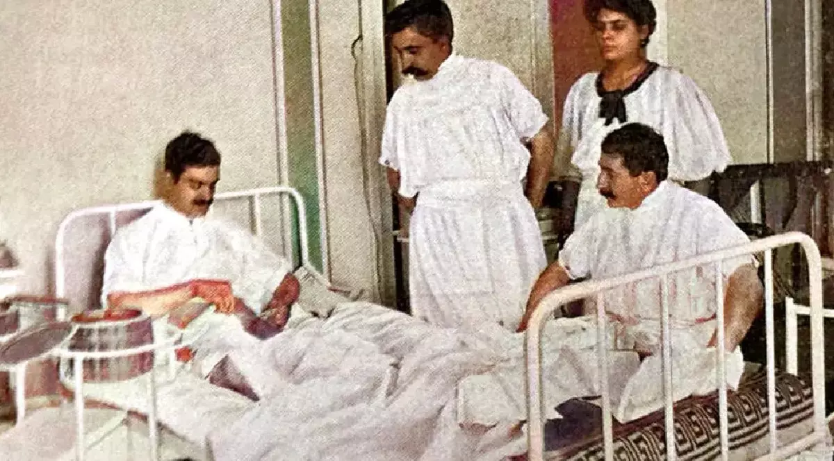 O poză din 1909, un medic se operează singur, într-un pat alb, din fier. Alți doi bărbați și o femeie, îmbrăcați în alb, îl asistă