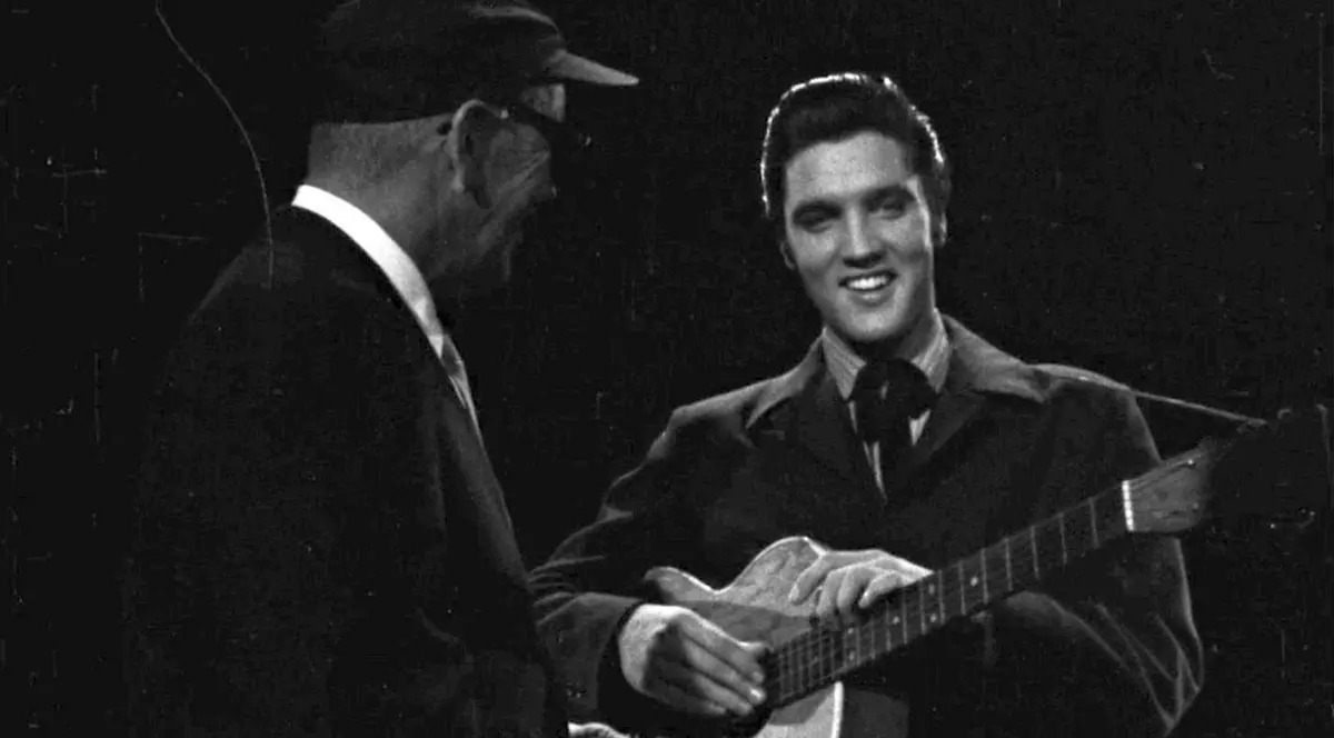 Elvis Presley cu chitara, râzând, la fostul Junco Studios din New York, pe 29 octombrie 1956