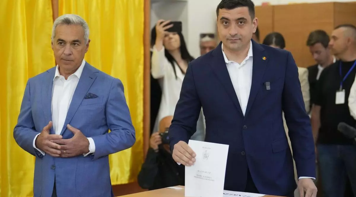 Candidatul AUR la prezidențiale George Simion (dreapta) introduce în urnă buletinul de vot și se află lângă Călin Georgescu, câștigătorul primului tur al alegerilor anulate de anul trecut, Mogoșoaia, duminică, 4 mai 2025.