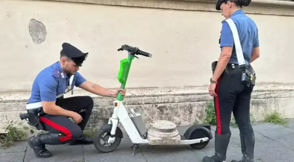 Doi polițiști din Roma, lângă o trotinetă electrică pe care este pusă o bucată dintr-o coloană romană.