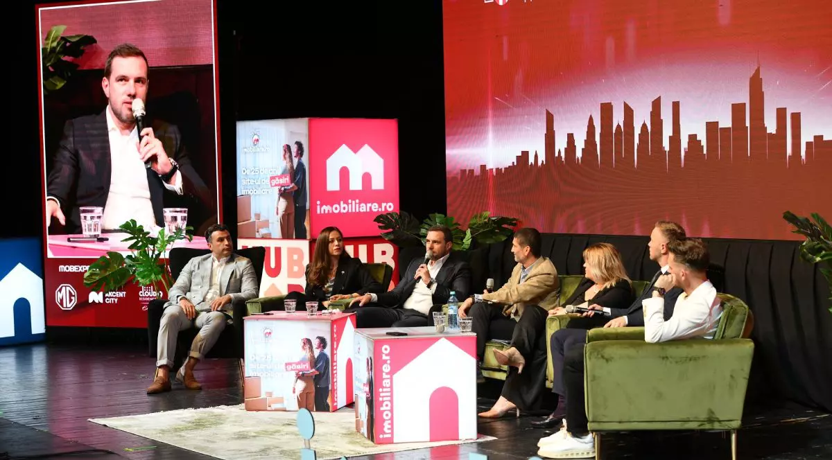 Dezvoltatori imobiliari, care stau pe scaune, în platoul Imobiliare.ro HUB Național 2025, pe fundal roșu, cu logo-ul Imobiliare.ro