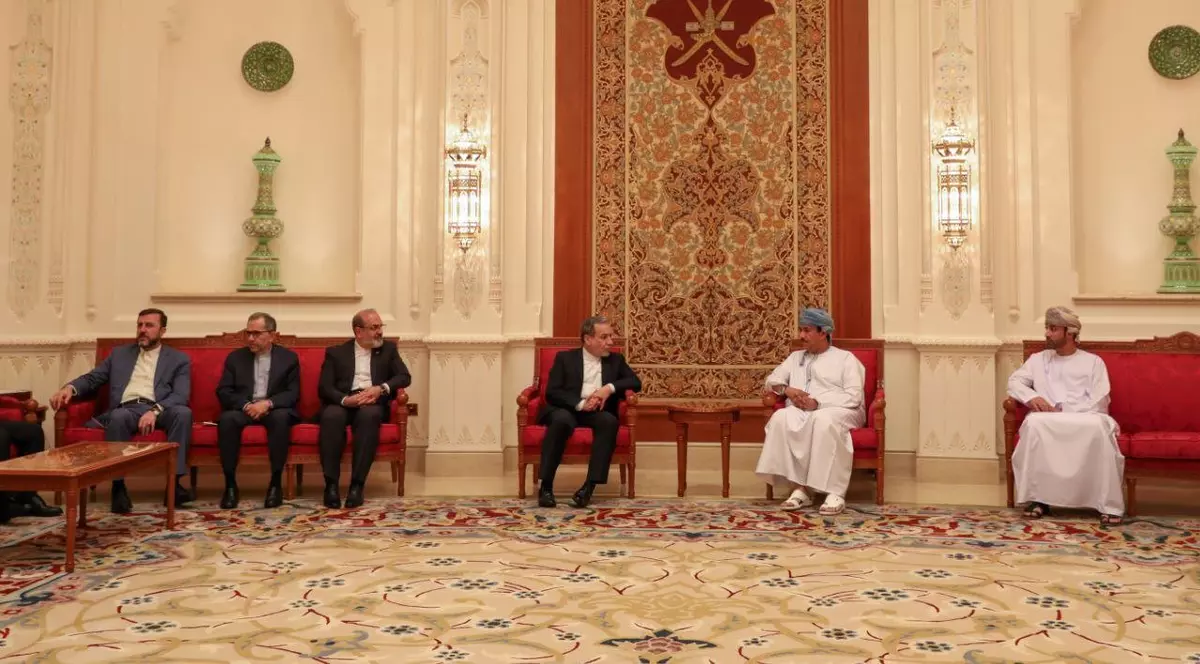 Ministrul iranian de externe, Abbas Araghchi (centru), discută cu un oficial omanez neidentificat la sosirea sa la Muscat, înainte de negocierile cu trimisul american pentru Orientul Mijlociu, Steve Witkoff