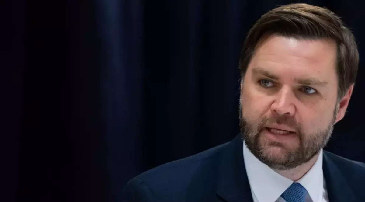 În imagine este ilustrat JD Vance, în costum albastru închis, cămașă albă și cravată albastră