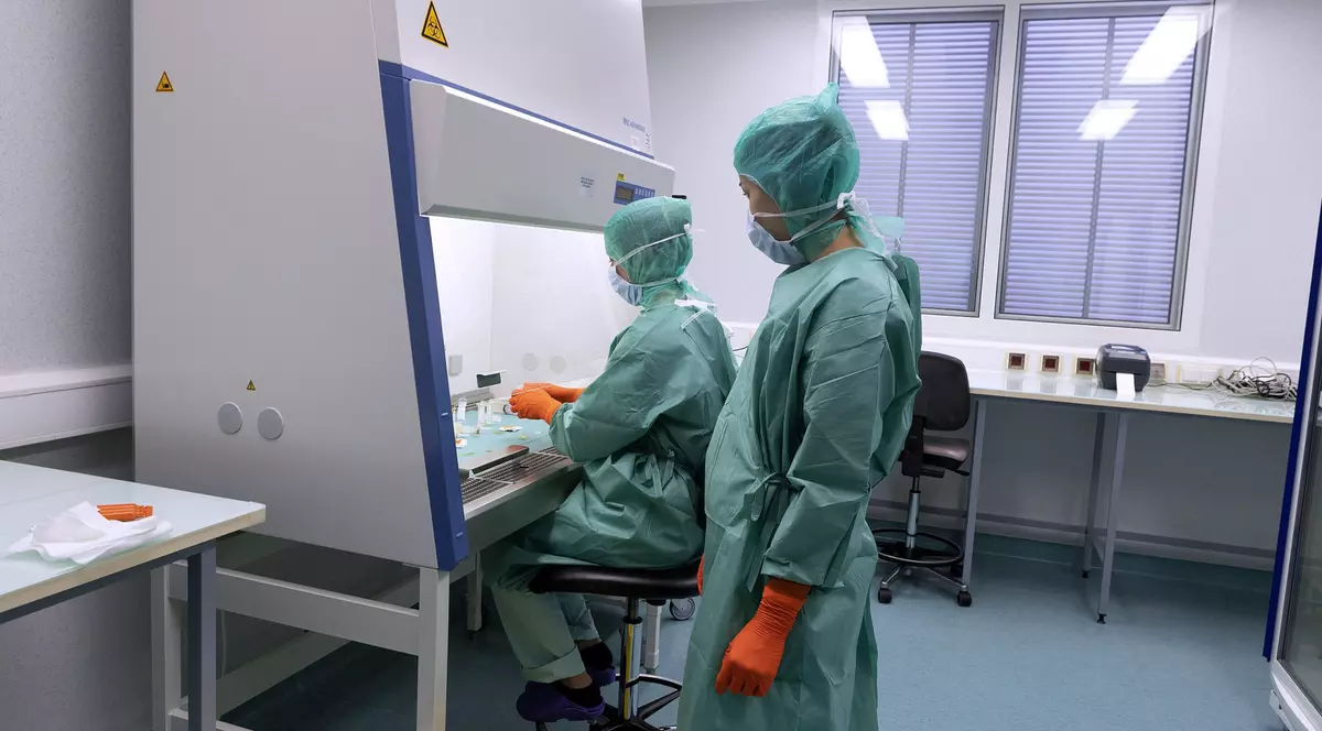 cercetători în halate verzi și cu măști într-un centru de cercetare biologică din franța