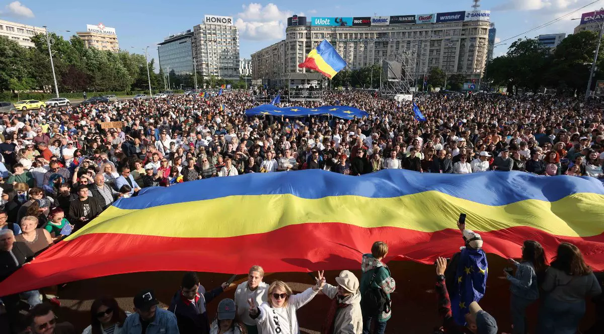 oameni prezenți la mitingul „România în Lumină” de duminică, 11 mai, 2025, țin deasupra lor un tricolor