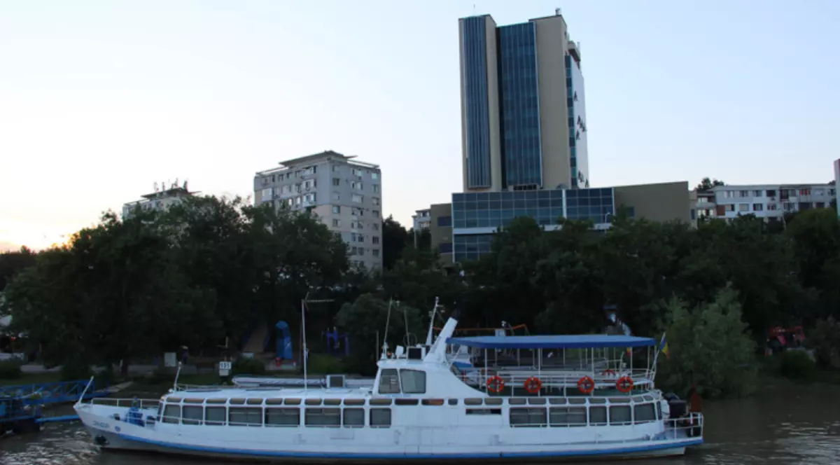 nava folosită de soții Ceaușescu plutește pe apa tulbure a Dunării iar pe fundal se văd o parte dintre clădirile orașului