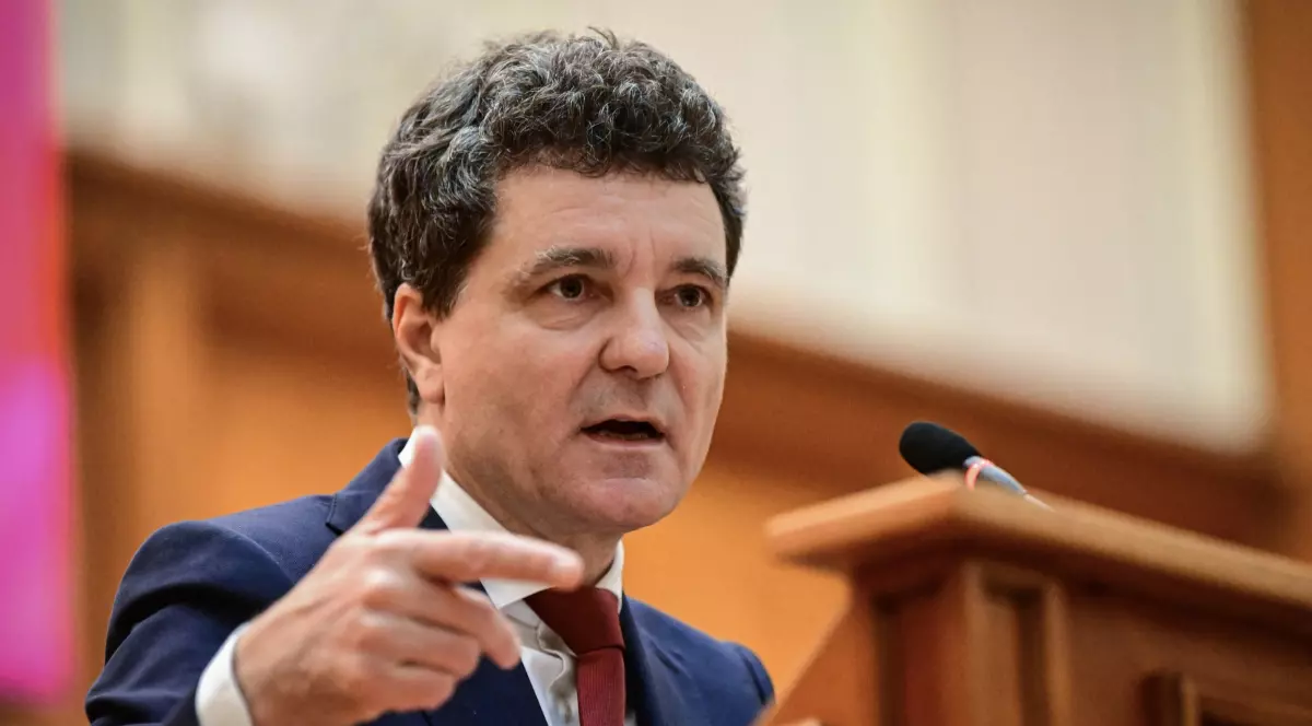 În imagine este ilustrat Nicușor Dan, în costum albastru închis, cămașă albă și cravată vișinie