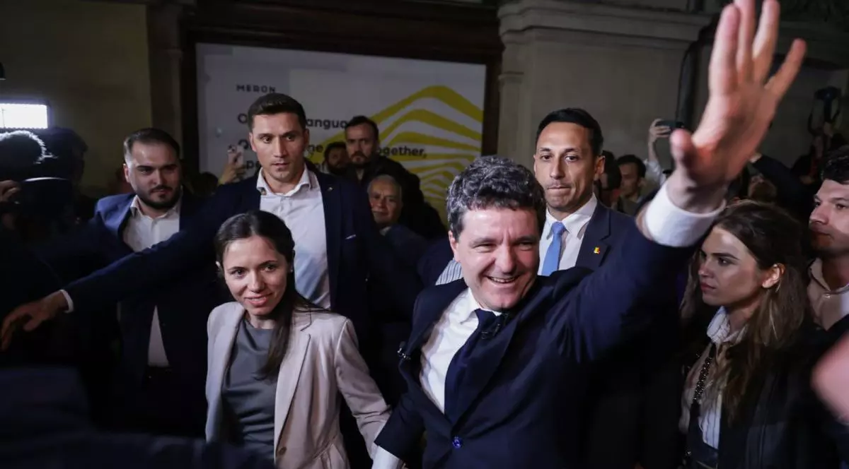 Nicușor Dan salută mulțimea și este de mână cu partenera sa, după ce a câștigat alegerile prezidențiale din România, 18 mai 2025, București
