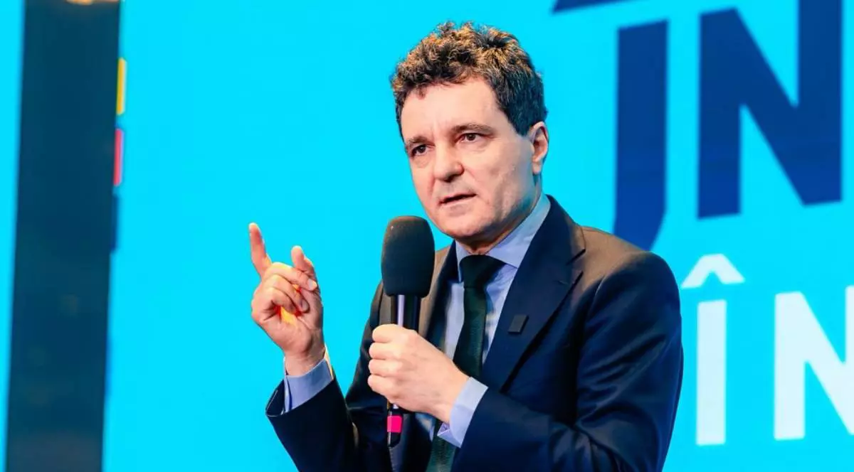 Nicușor Dan, îmbrăcat la costum, ține microfonul în mână în timpul unui discurs în campania electorală.