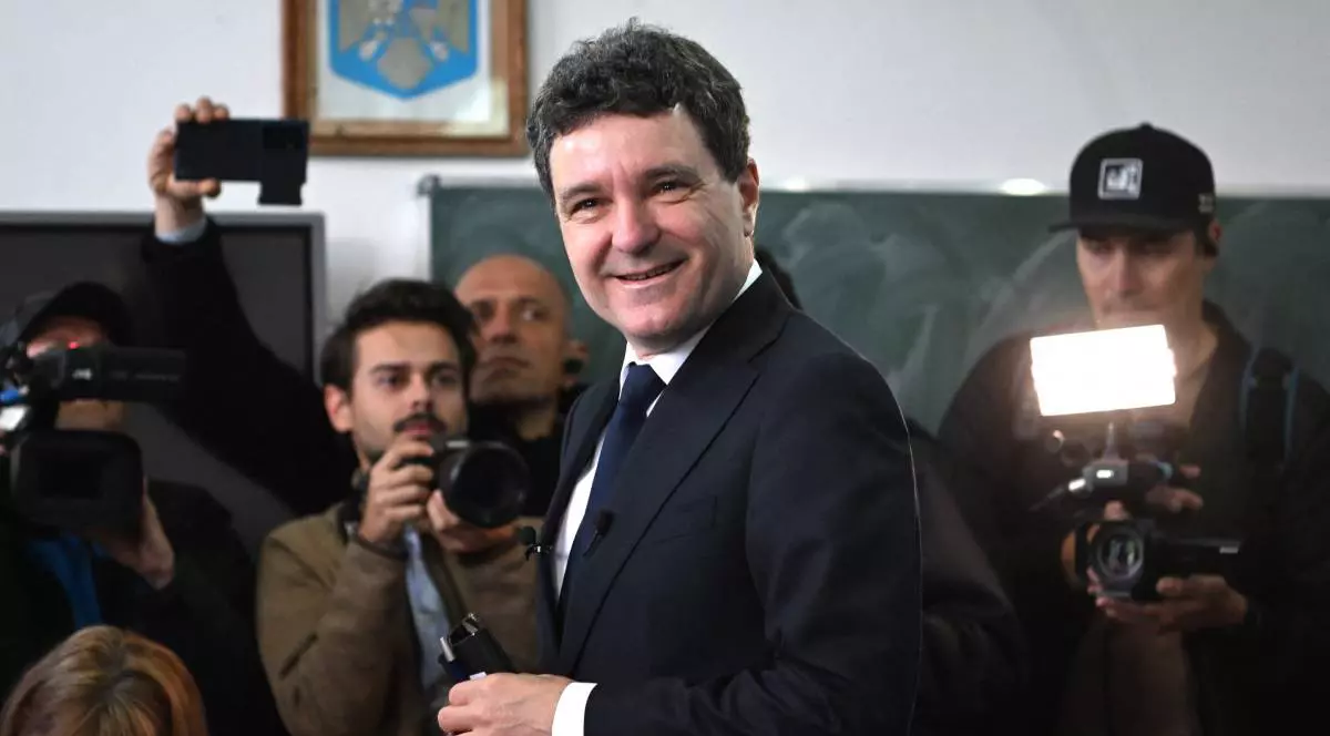 Nicușor Dan, îmbrăcat într-un costum negru, este vesel și înconjurat de jurnaliști și camere de filmat într-o sală de clasă