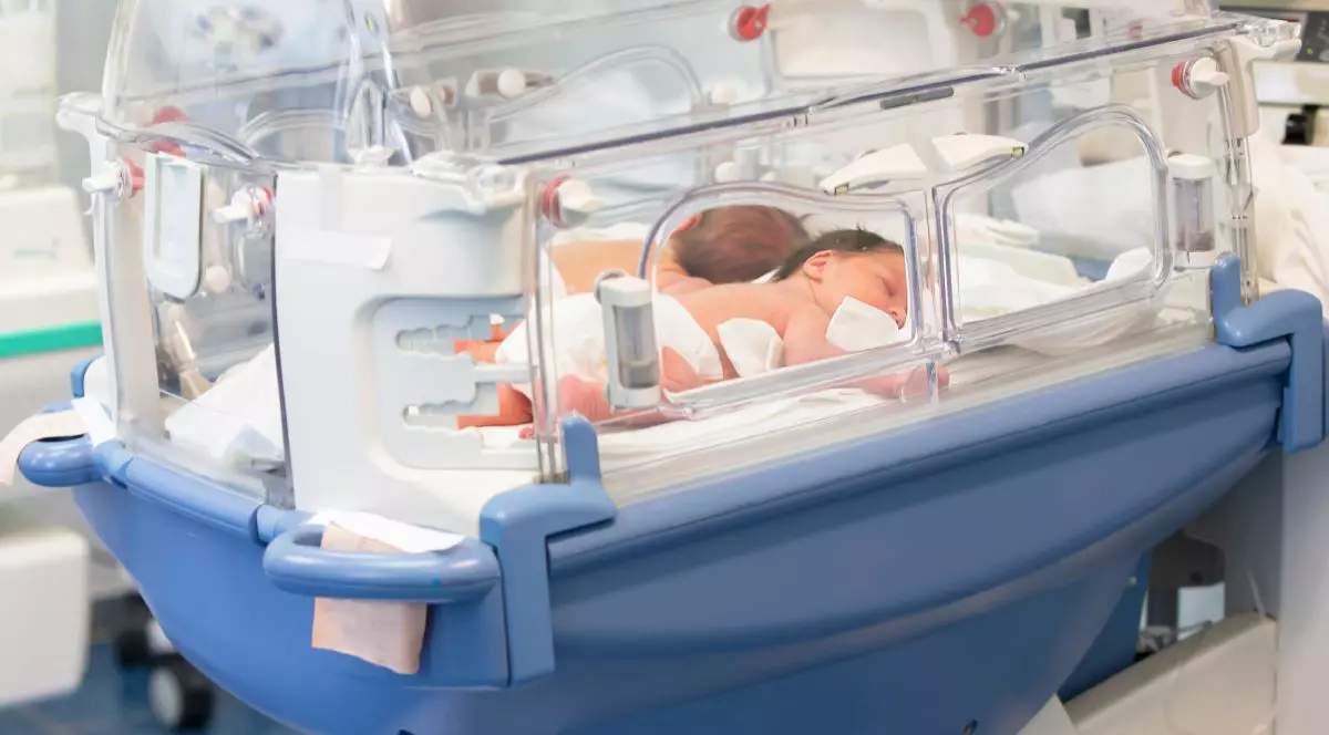 Doi bebelusi nou-născuți stau e burtică într0un incubator albastru in spital