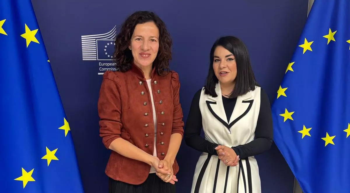 Oana Tache în Parlamentul European, alături de Roxana Mînzatu, cu steagurile Uniunii Europene în laterale.