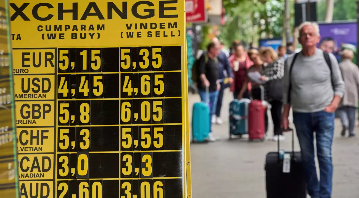 Oamenii trec pe lângă un panou de schimb valutar care afișează euro care crește la 5,35 lei, la o casă de schimb valutar din centrul Bucureștiului