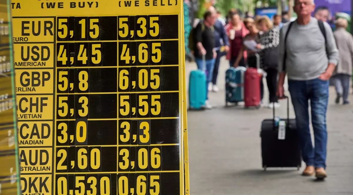 Oamenii trec pe lângă un panou de schimb valutar care afișează euro care crește la 5,35 lei, la o casă de schimb valutar din centrul Bucureștiului