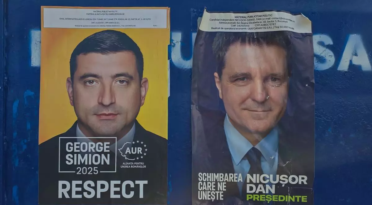 Un panou electoral albastru din București, pe care sunt două afișe cu candidații din turul 2 la alegerile prezidențiale: George Simion și Nicușor Dan