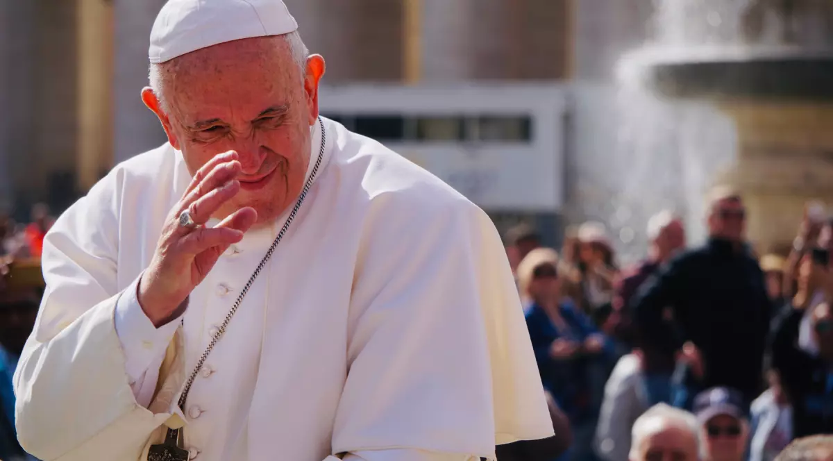 Papa Francisc, la Vatican, salutând mulțimea de oameni. Este îmbrăcat în haine specifice, albe, și are o cruce la gât.