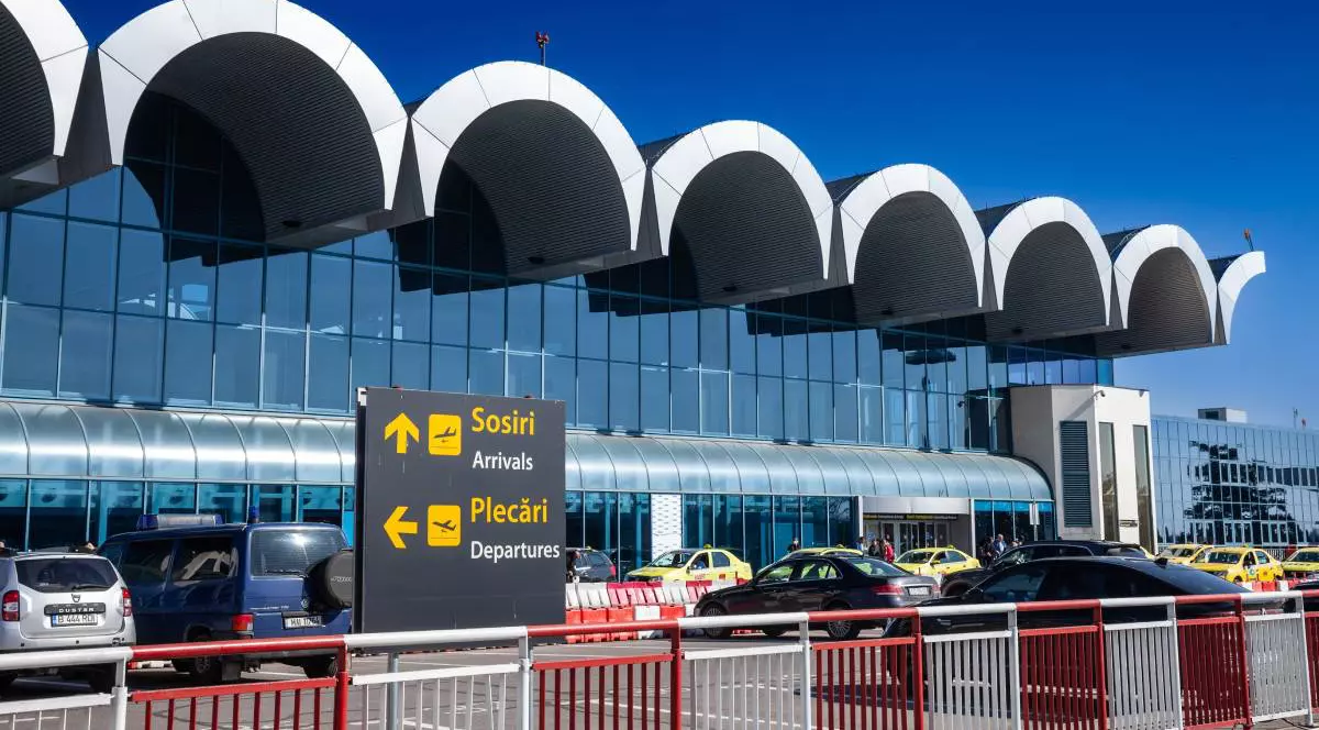 Parcarea din fața Aeroportului Otopeni, plină, într-o zi însorită.