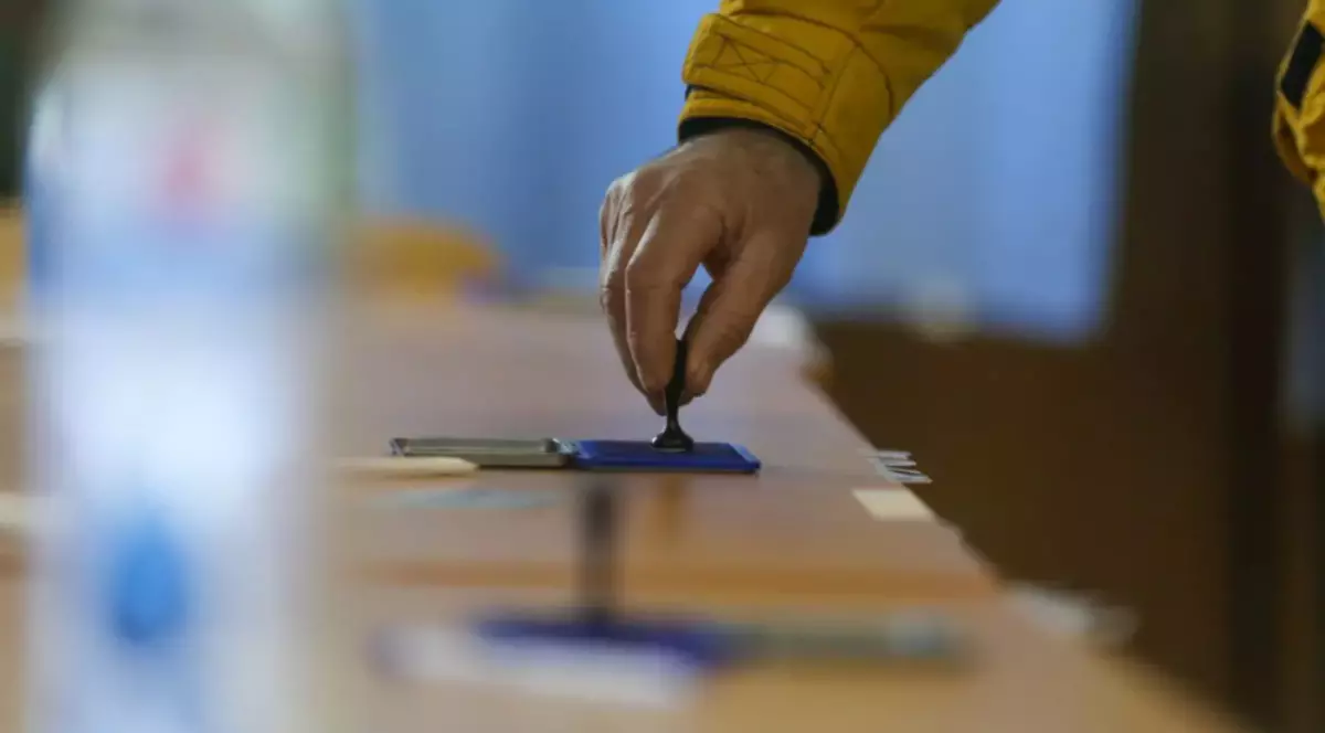 În imagine este ilustrată o persoană care ține o ștampilă de vot