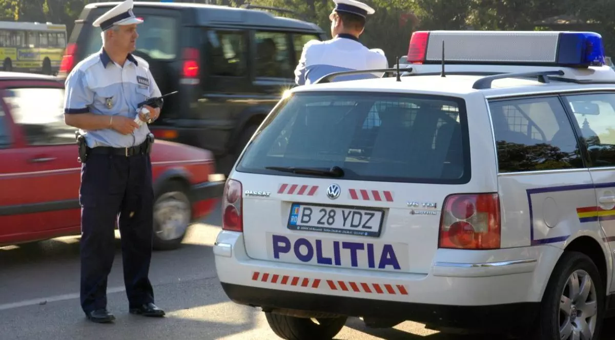 Polițisti pe stradă în București, vara, masini pe strada si o masină de poliție in prim-plan