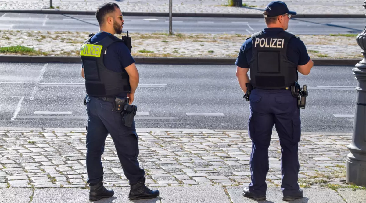 În imagine sunt ilustrați doi polițiști care se află pe un trotuar