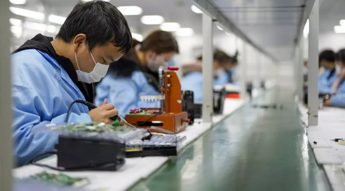 Angajații lucrează în atelierul unei companii de electronice din Chongqing, China